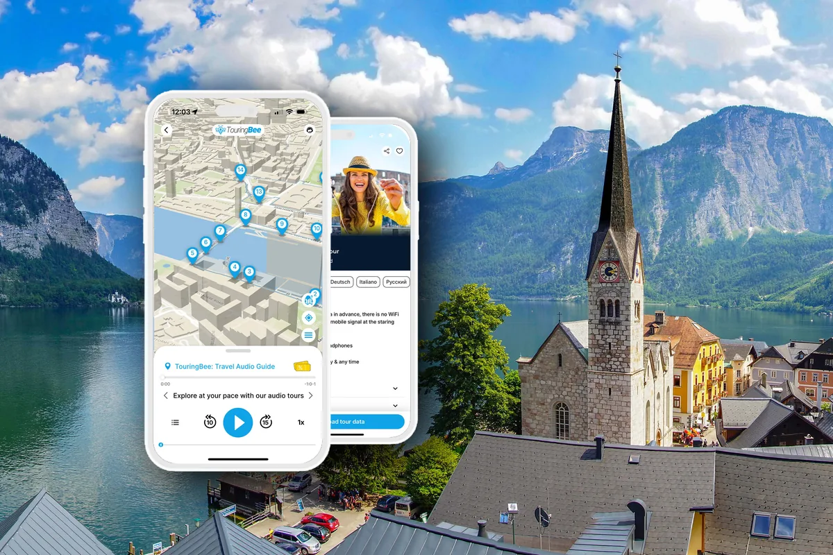 The TouringBee app showing the Hallstatt walking route on a phone, held up in front of the village